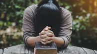 Hands folded in prayer on a Holy Bible in church concept for faith, spirituality and religion, woman praying on holy bible in the morning. woman hand with Bible praying. (Hands folded in prayer on a Holy Bible in church concept for faith, spirituality